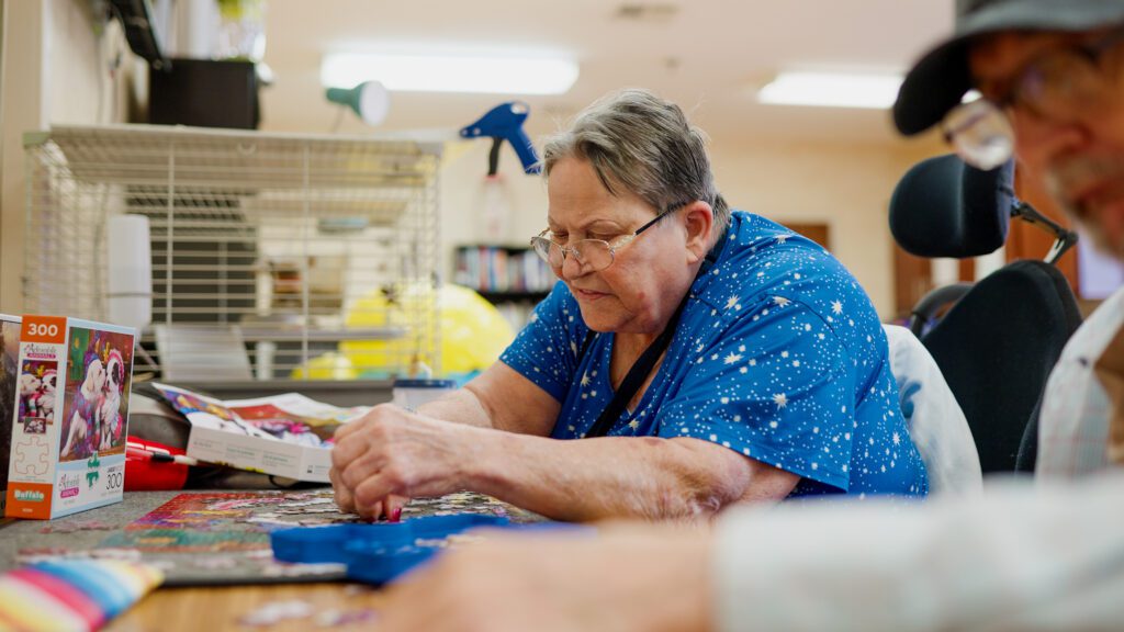 A woman puts together a puzzle at a skilled nursing facility