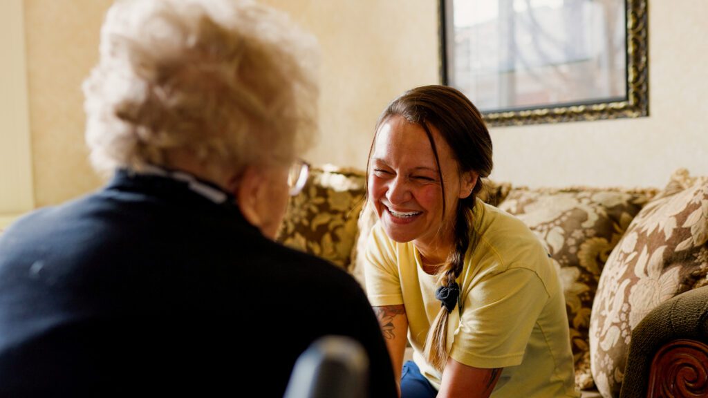 A woman smiles at a resident in a skilled nursing nursing home