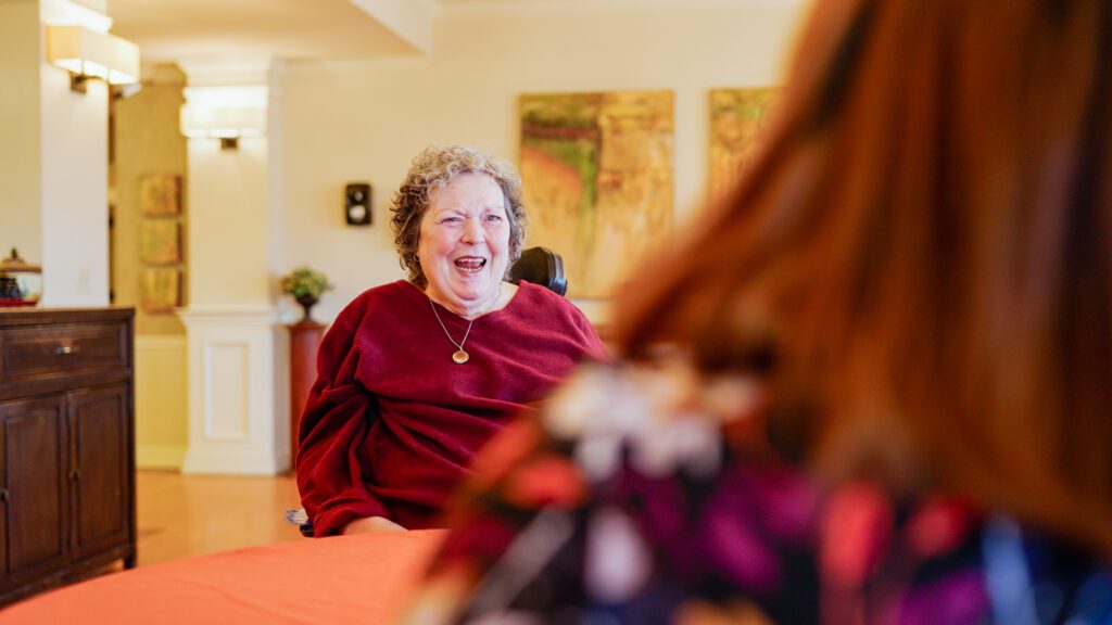 A woman smiles at the nurse in front of her at a respite care facility